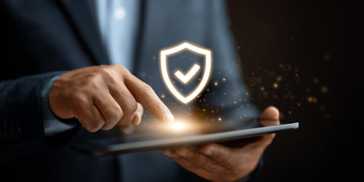 Businessman holding tablet with glowing security shield icon, cybersecurity and data protection concept