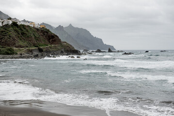 Fototapeta premium Dramatic coastal landscape of Tenerife, with rocky formations and crashing waves against a cloudy backdrop