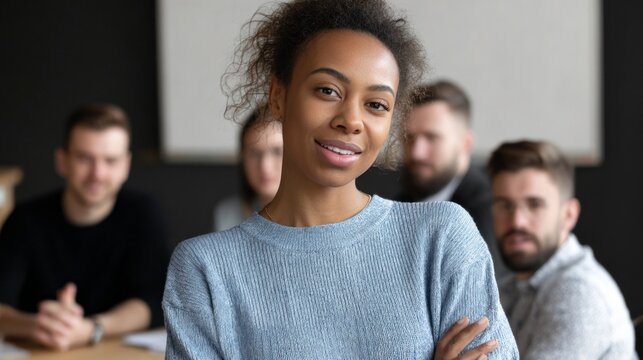 In a contemporary office, a confident woman stands at the forefront, smiling and presenting ideas