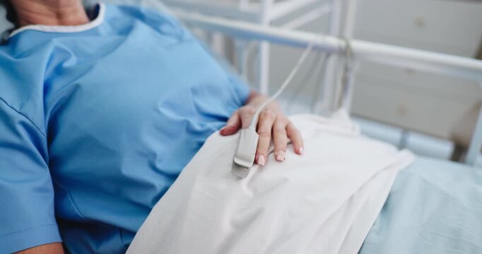 Medical, hand or patient in hospital with oximeter, surgery recovery or monitor in treatment rest. Healthcare, heart rate or person on bed with pulse meter, healing or oxygen track in post operation.