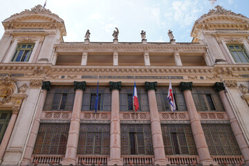 Fototapeta premium facade of the building of nice opera ornate european theater entrance with flags and columns