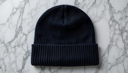 Dark blue knitted beanie hat with ribbed cuff on elegant white marble background, perfect for cold weather fashion.black beanie