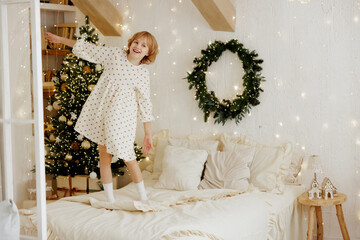 Joyful Child Jumping on Bed in Cozy Christmas Decorated Room