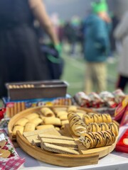 Assorted cookies displayed on a table at an outdoor event. Sweet pastries served at a festive gathering with people blurred in the background, perfect for food and lifestyle themes.