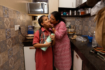 A mother lovingly kisses her daughter goodbye as she gets ready to leave for school
