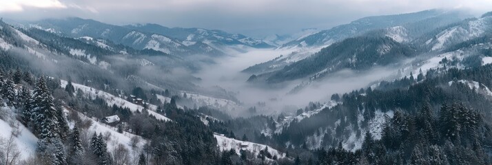 Panoramic view of snow covered mountains with mist in the valley winter