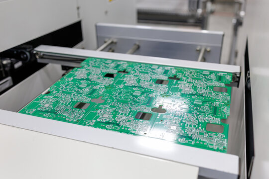 Green printed circuit board on automated electronics production line in factory