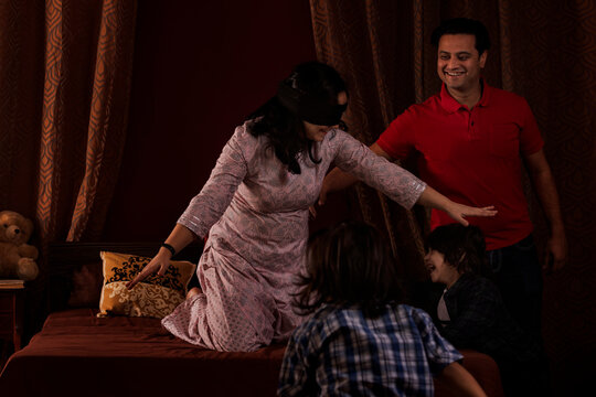 Parents playing hide and seek with their kids in bedroom