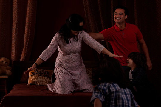 Parents playing hide and seek with their kids in bedroom