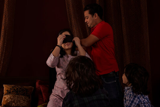 Parents playing hide and seek with their kids in bedroom