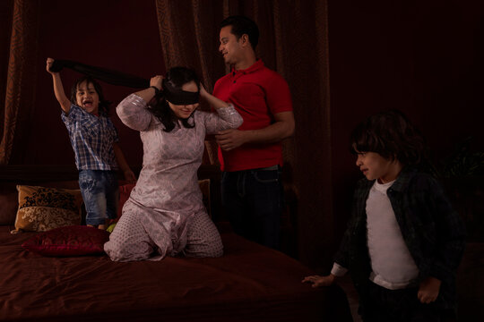 Parents playing hide and seek with their kids in bedroom
