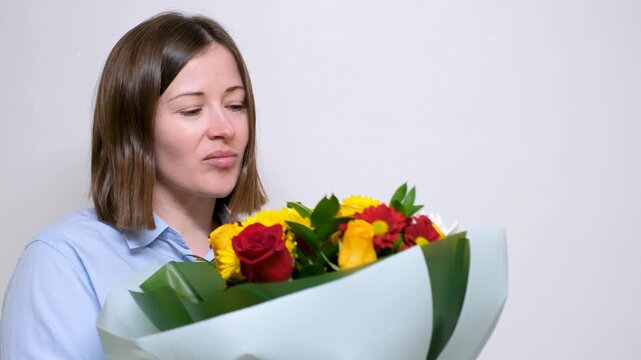 A young woman holds a chic bouquet of flowers of yellow roses and asters on white background.