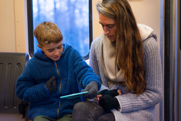 Mother and son using tablet on train during winter trip