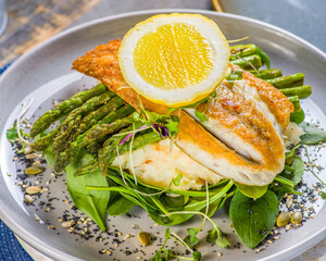 A succulent Barramundi fillet, served with tender asparagus spears and creamy mashed potato. Garnished with fresh basil leaves and finished with a slice of lemon on top.
