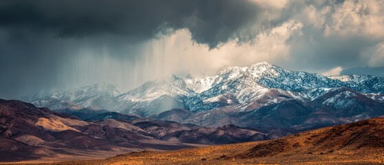 Snow capped mountains under dramatic stormy sky with rain falling image