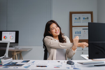 Happy businesswoman stretching arms at office desk