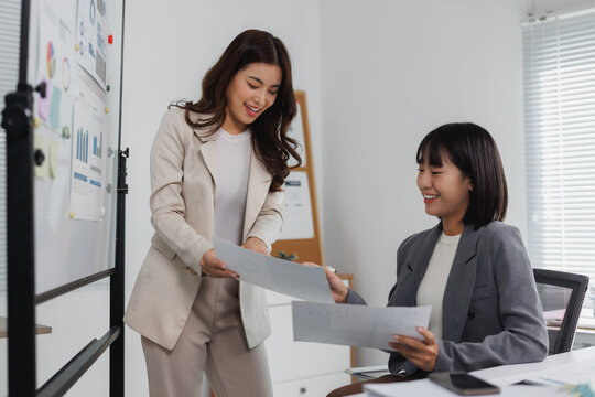 Businesswomen discussing market data in office - Powered by Adobe