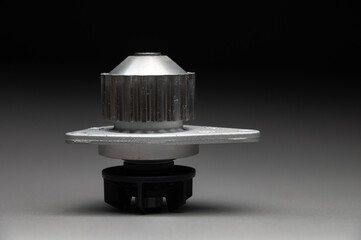 High-quality spare parts for your car. Car maintenance. New water pump for the engine cooling system on a gray gradient background.