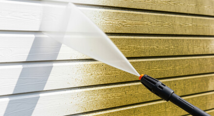 Power washing dirty house siding, a high pressure water jet cleaning the vinyl wall exterior. Before and after concept.