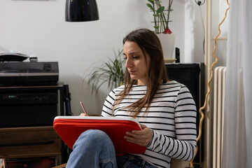 Young woman writing creating art in notebook at home