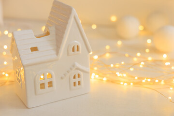 Decorative white ceramic house with warm lights for cozy home ambiance during winter season