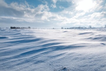 Drifting snow dunes under a cloudy blue sky with sun glare winter landscape