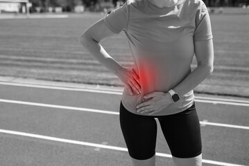 Girl in sportswear in stadium is exhausted and has pain during training and workout.Sports woman has a stomach ache.