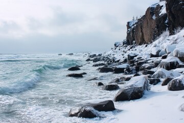 Snowy rocky coastline with crashing waves and icy formations under cloudy sky winter ocean