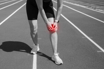 Close up and crop of woman's hand holding her knee after injury sustained during training.