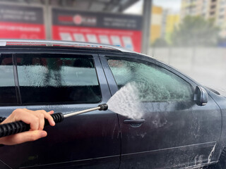 A man washes his car in a self-service sink.