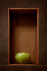 Still life with a green apple in a wooden box