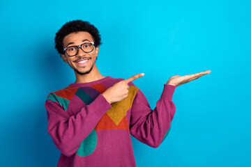 Stylish young man pointing with enthusiasm on blue background showcasing a concept of promotion and personality