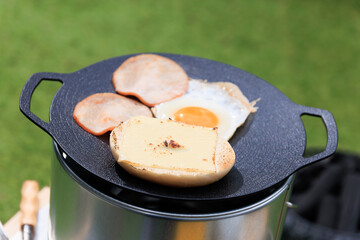 黒いマルチグリドルと具材のクローズアップ、芝生の緑を背景に