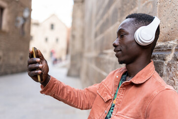 African man taking selfie with cell phone on city street during travel vacation