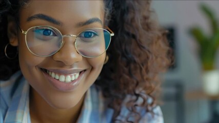 A smiling young woman wearing glasses with blue eyes looking directly at the camera. She has an office setting in the background and appears confident and approachable.