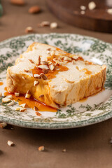 A detailed close-up showcases a slice of traditional caramelized egg white pudding known as molotof or molotov, generously drizzled with sweet caramel syrup and sprinkled with almond pieces