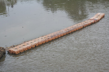 Obraz premium Floating modular barrier installed on a river to control debris and waste movement.