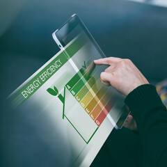 Woman uses a tablet to monitor home's energy efficiency. Energy conservation and environmental...