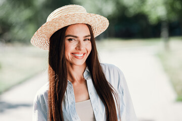 Playful sunny day in the park smiling stylish woman wearing a hat and light shirt during a spring...
