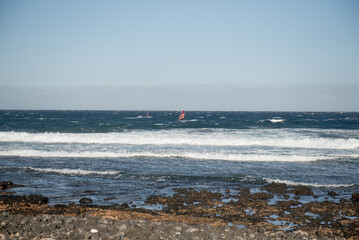 Windsurfers navigating the waves off the coast of Tenerife, showcasing the vibrant ocean and clear blue skies
