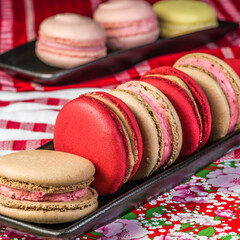 A row of macaroons, alternating between red and cream hues, are aligned and ready to be enjoyed.