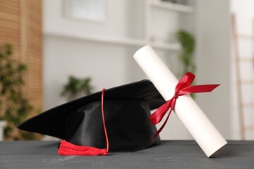 Diploma and graduation hat on grey wooden table indoors, closeup. Space for text