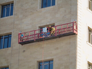 The worker in the construction cradle. Apartment building under construction. Ust-Kamenogorsk (kazakhstan)