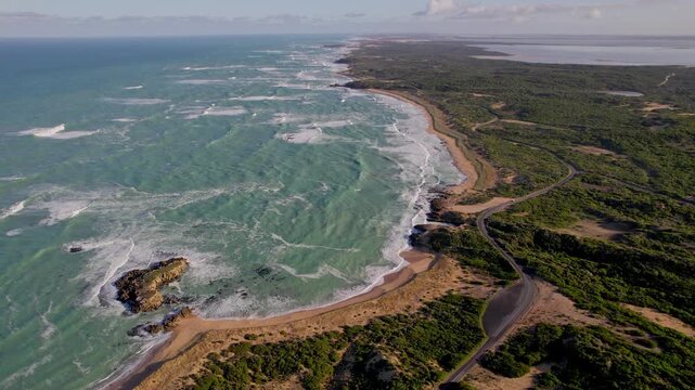 Aerial coastal view of Beachport, South Australia, showing the road running along the shoreline. Clear water, rocky edges and coastal scenery create a vivid landscape.