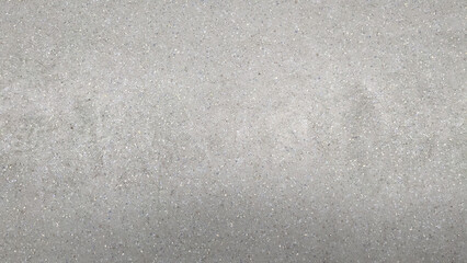 Close-up of a textured concrete surface with small embedded stones, showcasing a neutral gray...