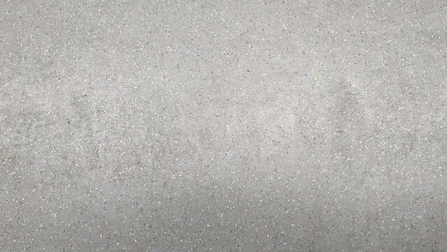 Close-up of a textured concrete surface with small embedded stones, showcasing a neutral gray industrial aesthetic.