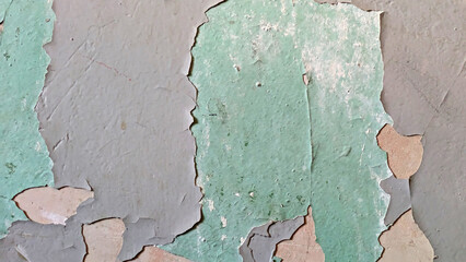 Close-up of peeling green paint on a weathered wall, showing texture and decay.