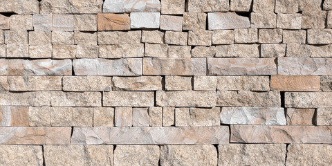 A close-up view of a textured stone wall with natural beige and gray tones, showcasing a rustic and durable masonry pattern. Travertine wall