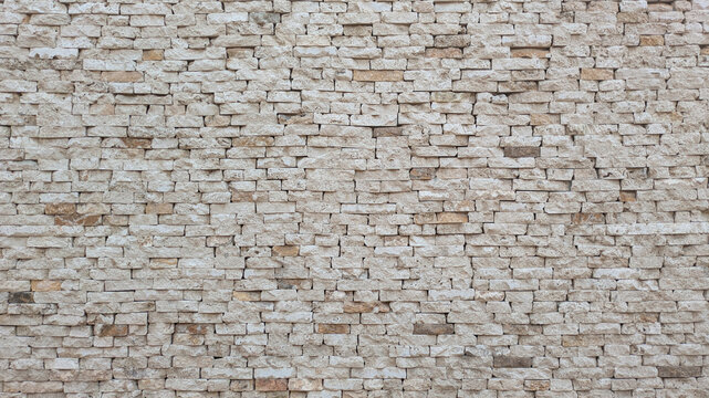 A textured stone wall with irregularly stacked beige and cream-colored stones, showcasing natural patterns and rustic charm. Travertine wall