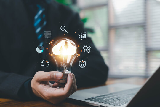 A glowing cloud computing icon inside a light bulb held near a laptop represents digital transformation, data management, cybersecurity, innovative cloud technology solutions for modern businesses.